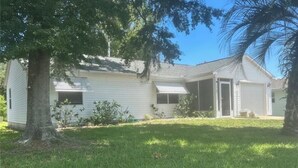 Ein Bungalow mit überdachter Veranda, Garage und Rasen.