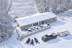 A house with a covered patio, a truck, and three snowmobiles parked in front. - Snowmobile, Fish & Relax: Mink Lake Retreat (Buffalo)