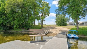 A riverside walkway with a dock, a bench, and a small boat. - Fish & Relax Fireside: Mink Lake Retreat! (Buffalo)