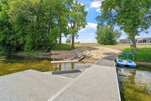 A riverside walkway with a dock, a bench, and a small boat. - Fish & Relax Fireside: Mink Lake Retreat! (Buffalo)