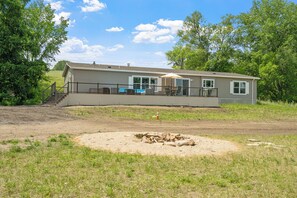 A single-story house with a deck, a fire pit, and a covered outdoor seating area. - Fish & Relax Fireside: Mink Lake Retreat! (Buffalo)