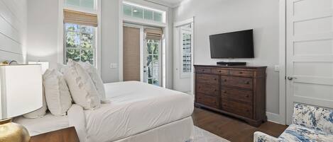 Un dormitorio con cama, cómoda, televisor y una silla.