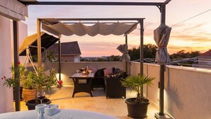 A rooftop patio with a hot tub, outdoor furniture, and potted plants. - Stylish Duplex with Private Jacuzzi (Ližnjan)