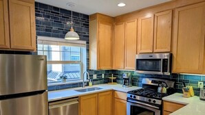A modern kitchen with wooden cabinets, stainless steel appliances, and a large window. - Chalet 113 at the Official Collins Lake Resort (Government Camp)