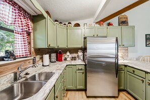 A kitchen with green cabinets, stainless steel appliances, and a window with a checkered curtain. - Pet Friendly Rustic 2-bedroom chalet in charming Gatlinburg (Gatlinburg)