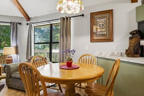 A dining area with a round wooden table, chairs, a potted plant, and a framed picture on the wall. - Pet Friendly Rustic 2-bedroom chalet in charming Gatlinburg (Gatlinburg)