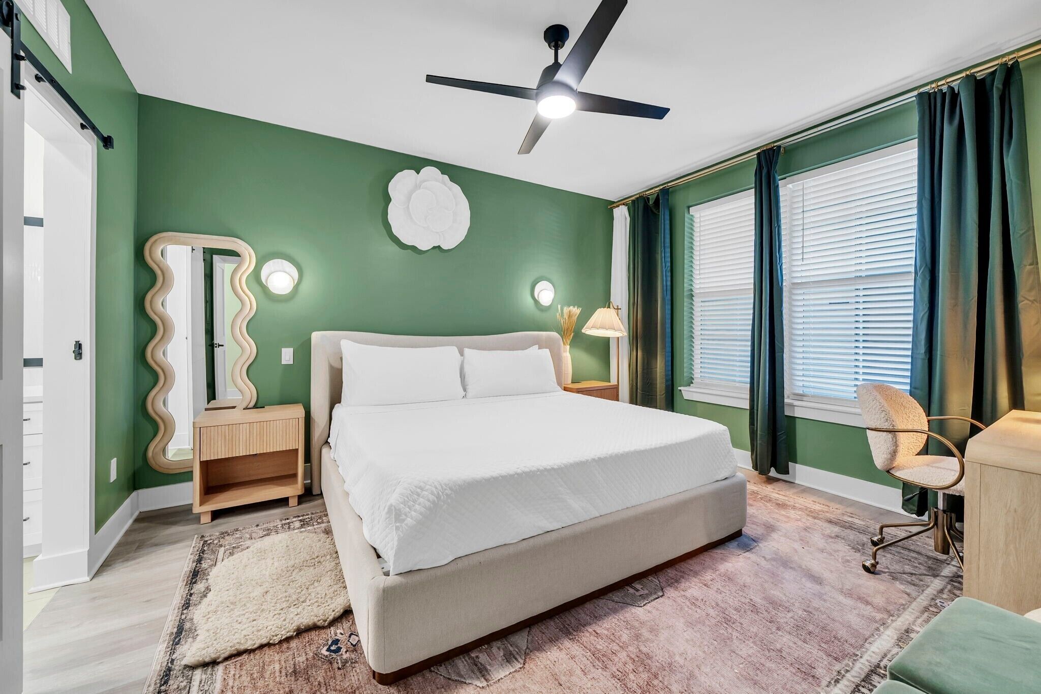 A bedroom with a bed, a ceiling fan, a bedside table, a lamp, and a chair.