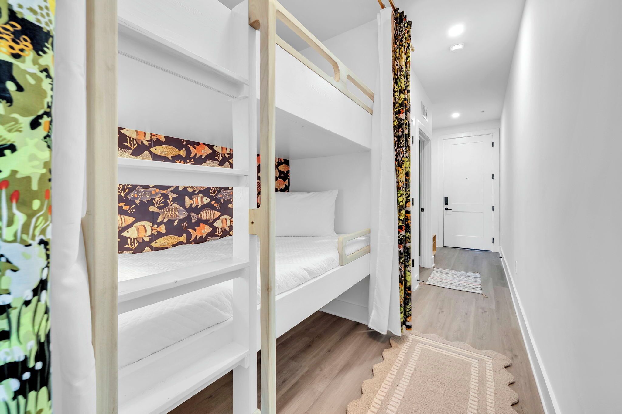 A bunk bed room with a patterned headboard, a white door, and a wooden floor.