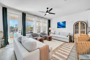 A modern living room with a sofa, armchairs, a coffee table, and a ceiling fan. - The Grove Juniper 224 - 1 Bedroom - Lazy River - Seascape Resort (Miramar Beach, FL)