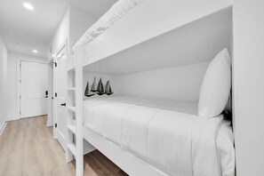 Ein Etagenbett mit weißer Bettwäsche und eine Tür im Hintergrund.