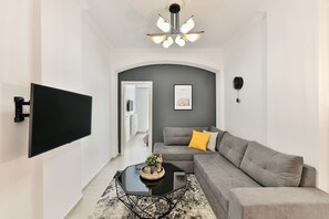 Ein modernes Wohnzimmer mit einem grauen Sofa, einem schwarzen Couchtisch und einem an der Wand befestigten Fernseher.
