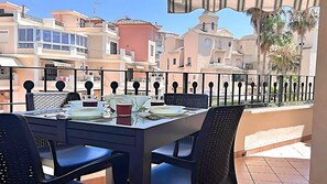 Un balcon avec une table dressée pour le dîner, donnant sur un quartier résidentiel composé de plusieurs immeubles.