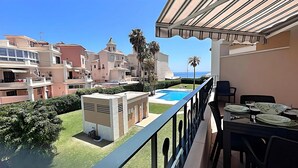 A balcony with a pool, overlooking a residential area with multiple buildings and a clear view of the sea. - Euromar 121 (Torrox)