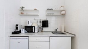 A kitchen with white cabinets, a dishwasher, a microwave, a coffee maker, and a sink.