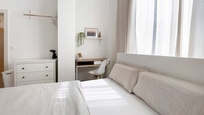A bedroom with a bed, a desk, and a chair.