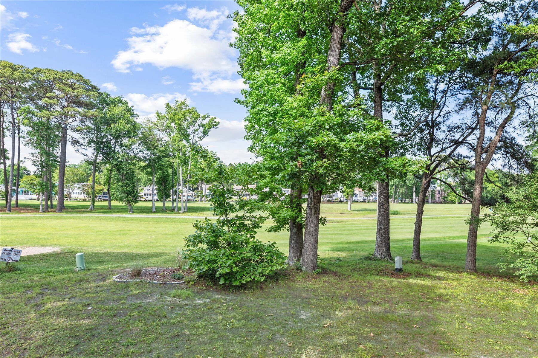 A golf course with well-maintained grass, trees, and a clear sky.