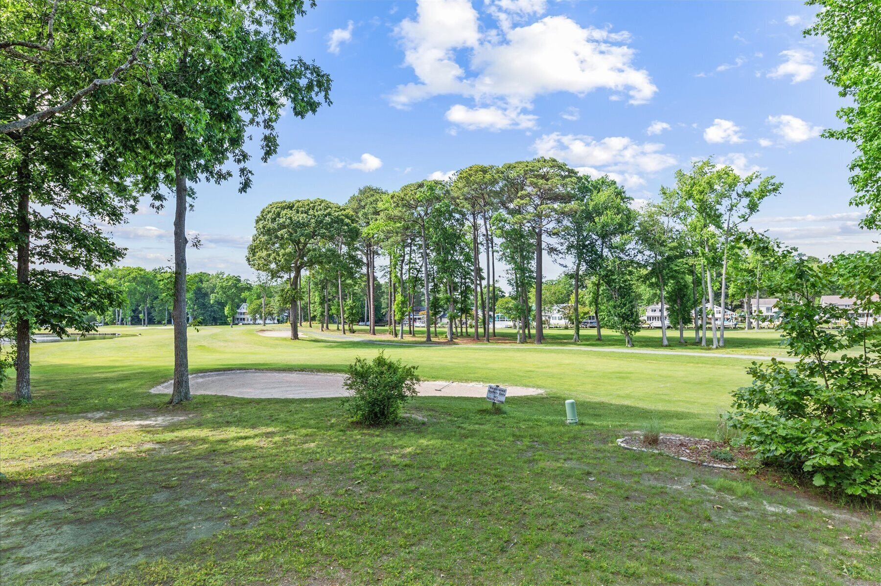 Een golfbaan met een putting green, zandbunkers en een vlag.