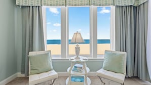 Une chambre avec vue sur la plage, comprenant un canapé blanc, une petite table avec une lampe et une bibliothèque.