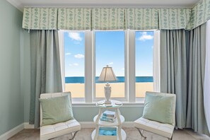 A room with a view of the beach, featuring a white sofa, a small table with a lamp, and a bookshelf. - Belmont Towers 502 by Seaside Vacations & Sales (Ocean City)