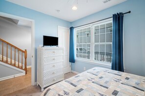A bedroom with a bed, a dresser, a TV, a window with blinds, and a staircase. - Captain View Villa 3 by Seaside Vacations & Sales (Ocean City)