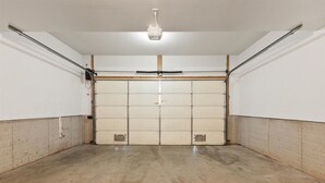 Een garage met een betonnen vloer, witte wanden en een gesloten garagepoort.