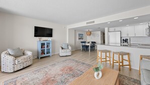 Ein modernes Wohnzimmer mit einer Couch, einem Couchtisch und einem Essbereich mit Stühlen und einem Teppich.