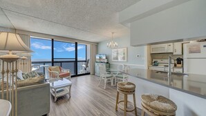 Een ruime woonkamer met een groot raam, een eethoek en een keuken met moderne apparatuur.