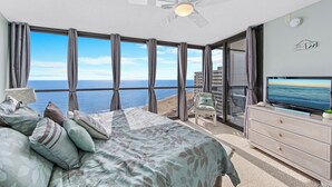 Un dormitorio con cama, televisor, cómoda y vista al océano.