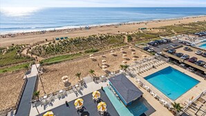 Un complexe hôtelier doté d’une piscine, d’une plage et de chaises longues.
