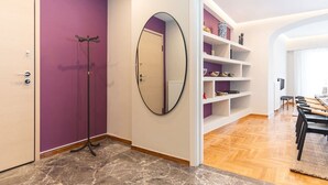 A modern interior with a purple wall, a wooden floor, a mirror, and a white shelving unit with decorative items. - The MP10 Residence - Kolonaki (Athens)