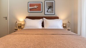 A bedroom with a large bed, two white pillows, a brown headboard, and two framed pictures on the wall. - The MP10 Residence - Kolonaki (Athens)