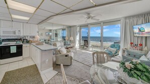 Een ruime woonkamer met keuken, een eettafel en een balkon met uitzicht op zee.