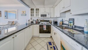 A kitchen with white cabinets, a microwave, an oven, a sink, and a dishwasher. - Ocean view condo Seaside Vacations & Sales (Ocean City)