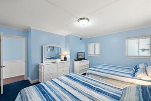 A bedroom with two beds, a dresser, a mirror, and a ceiling light. - Stunning oceanfront condo by Seaside Vacations & Sales (Ocean City)