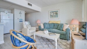 Una sala de estar con un sofá, sillones, una mesa de centro y un refrigerador.