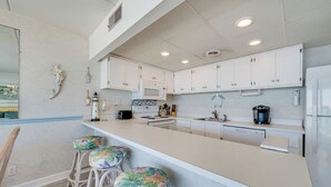 Una cocina moderna con armarios blancos, una isla grande con taburetes y un microondas.