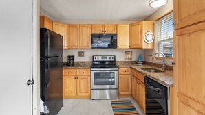 A kitchen with wooden cabinets, a stainless steel refrigerator, a microwave, an oven, and a dishwasher. - Seas the Day 1 by Seaside Vacations & Sales (Ocean City)
