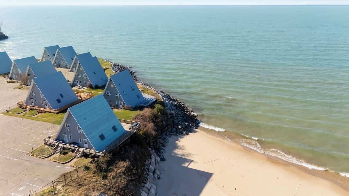 A coastal property with multiple houses, a sandy beach, and a rocky shoreline.