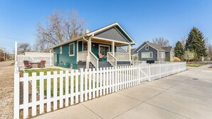 A two-story house with a white picket fence, a covered porch, and a front yard. - Kanon’s Kottage | Downtown Retreat Near RMNP (Loveland)