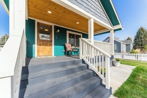 A front porch with a wooden deck, a covered entryway, and a small outdoor seating area with a chair and table. - Kanon’s Kottage | Downtown Retreat Near RMNP (Loveland)