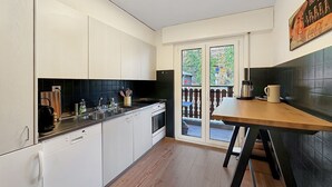 Eine moderne Küche mit weißen Schränken, einer schwarzen Spritzschutzwand und einem Holzespeisetisch.