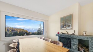 Ein Essbereich mit großem Fenster, Kamin und einem Gemälde an der Wand.