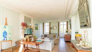 A spacious living room with a wooden floor, a sofa, a coffee table, and a dining table. - Domaine de Vauluisant, gîte for 32 people in Burgundy (COURGENAY)