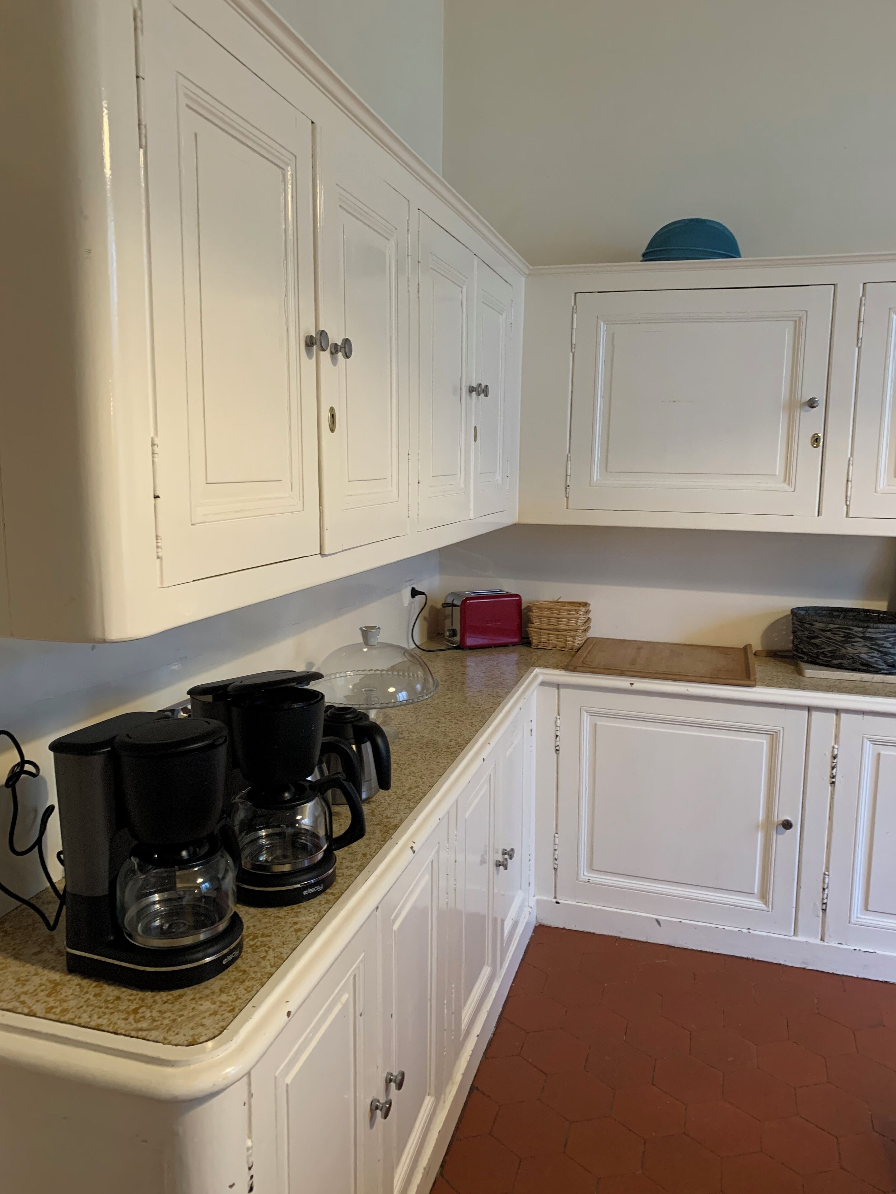 A kitchen with white cabinets, a granite countertop, and a coffee maker.