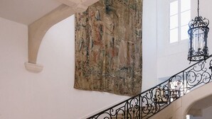 A grand staircase with ornate black balustrades, a large classical painting on the wall, and a traditional oil lamp on a wooden table. - Domaine de Vauluisant, gîte for 32 people in Burgundy (COURGENAY)