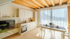 A modern kitchen with white cabinets, a wooden ceiling, and a dining area with a table and chairs. - L'Oro di Pizzon - Frantoio | Pool & Garden (Pizzon)