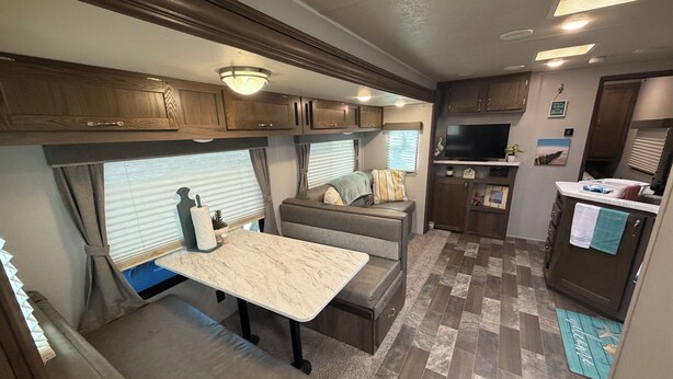 Een compact camperinterieur met een kitchenette, zithoek en een televisie.