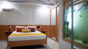 A modern hotel room with a large bed, wooden headboard, and a built-in aquarium.