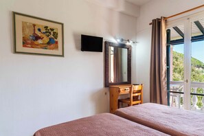 Ein Schlafzimmer mit zwei Betten, einem Holztisch, einem Fernseher und einem großen Spiegel.