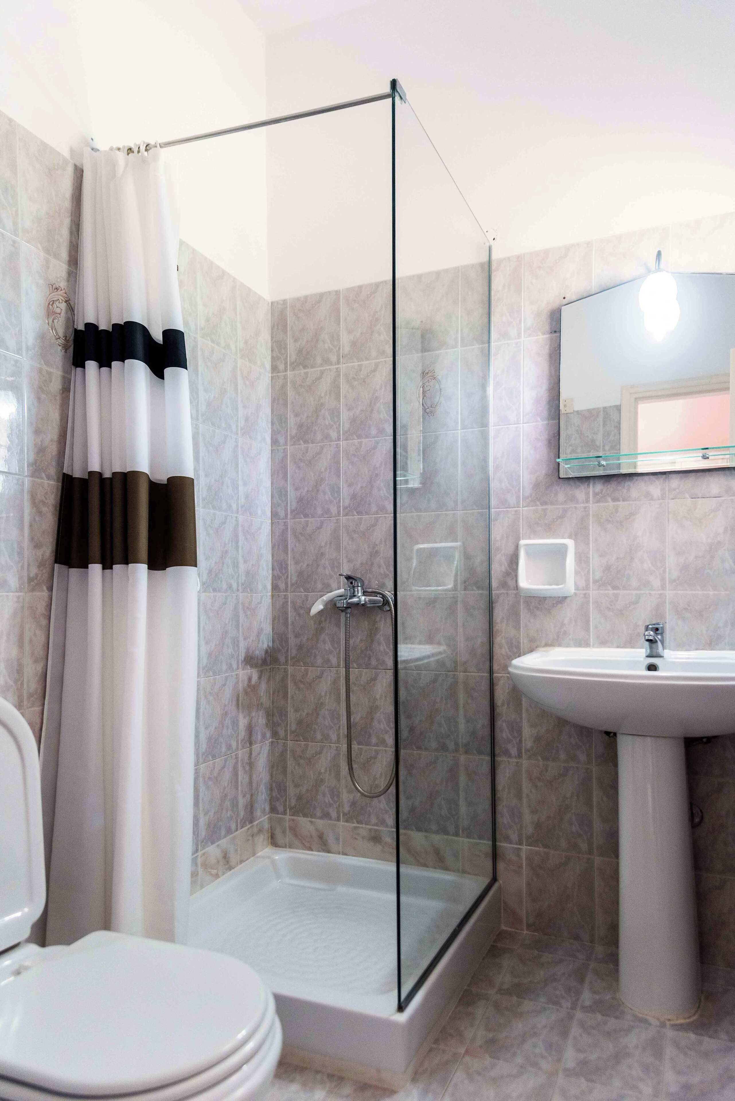 Ein modernes Badezimmer mit einer Duschkabine, einem Standwaschbecken und einer Toilette.